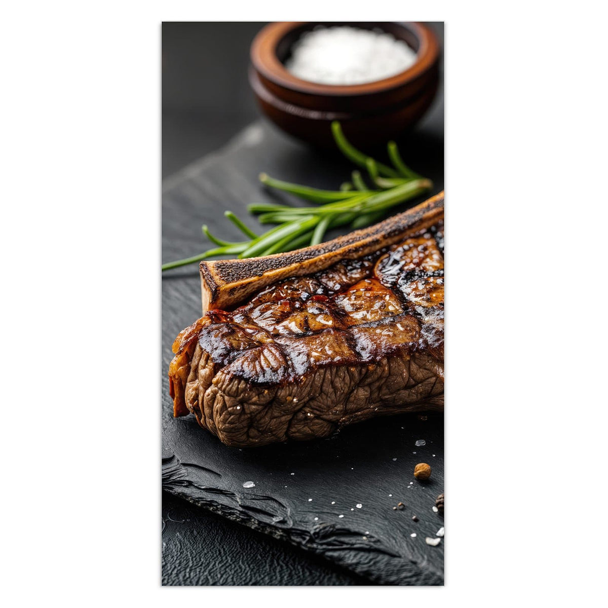 Angeschnittenes T-Bone-Steak mit Grillstreifen auf Schiefer, dazu Rosmarin, Salzschale und Pfefferkörner