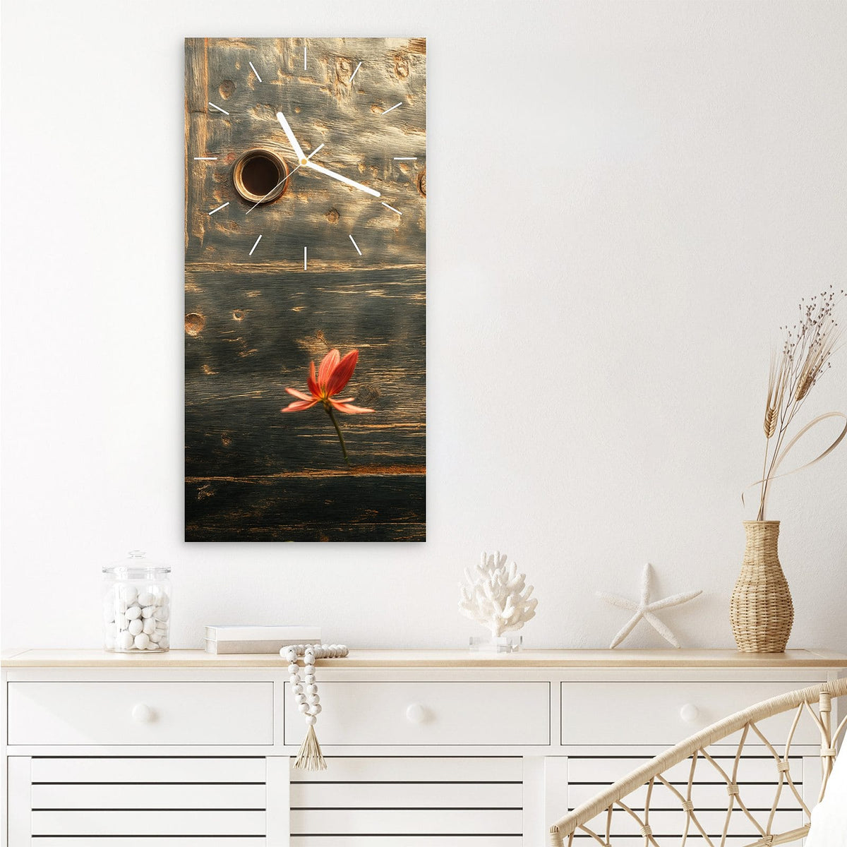 Wanduhr aus Glas im Hochformat Rote Blüten am Metall mit Ziffernblatt Linie über einem weißen Sideboard
