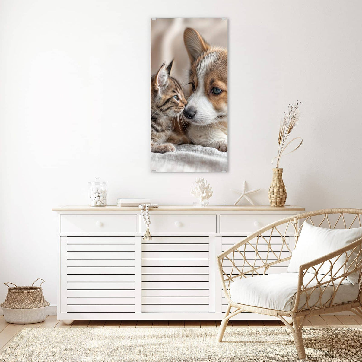 Wandbild aus Glas Welpe und Kätzchen über einem weißen Sideboard neben einem Rattansessel