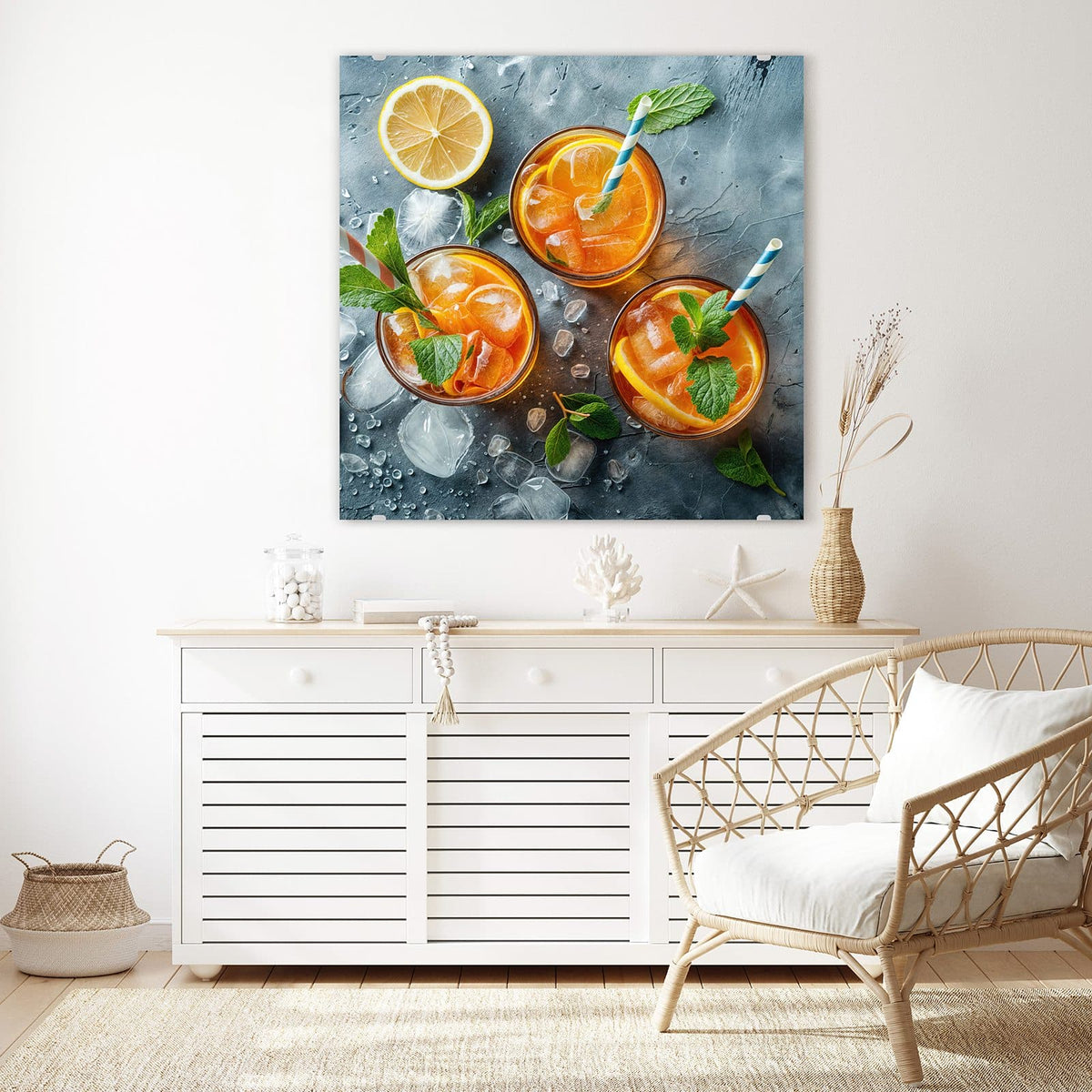 Glasbild Drei Drinks mit Zitrone an der Wand – Drei Gläser mit orangefarbenem Eisgetränk, Zitrusscheiben, Minze und Papierstrohhalmen, daneben eine halbe Zitrone auf grauem Stein