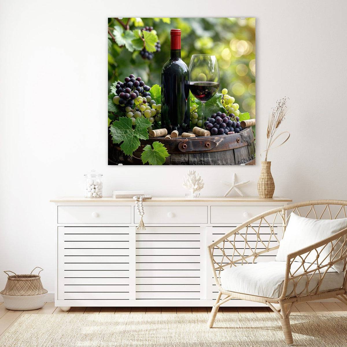 Glasbild Rotwein auf Holzfass an der Wand – Rotweinflasche und gefülltes Glas auf einem Holzfass, umgeben von blauen und grünen Trauben, Korken und Weinlaub