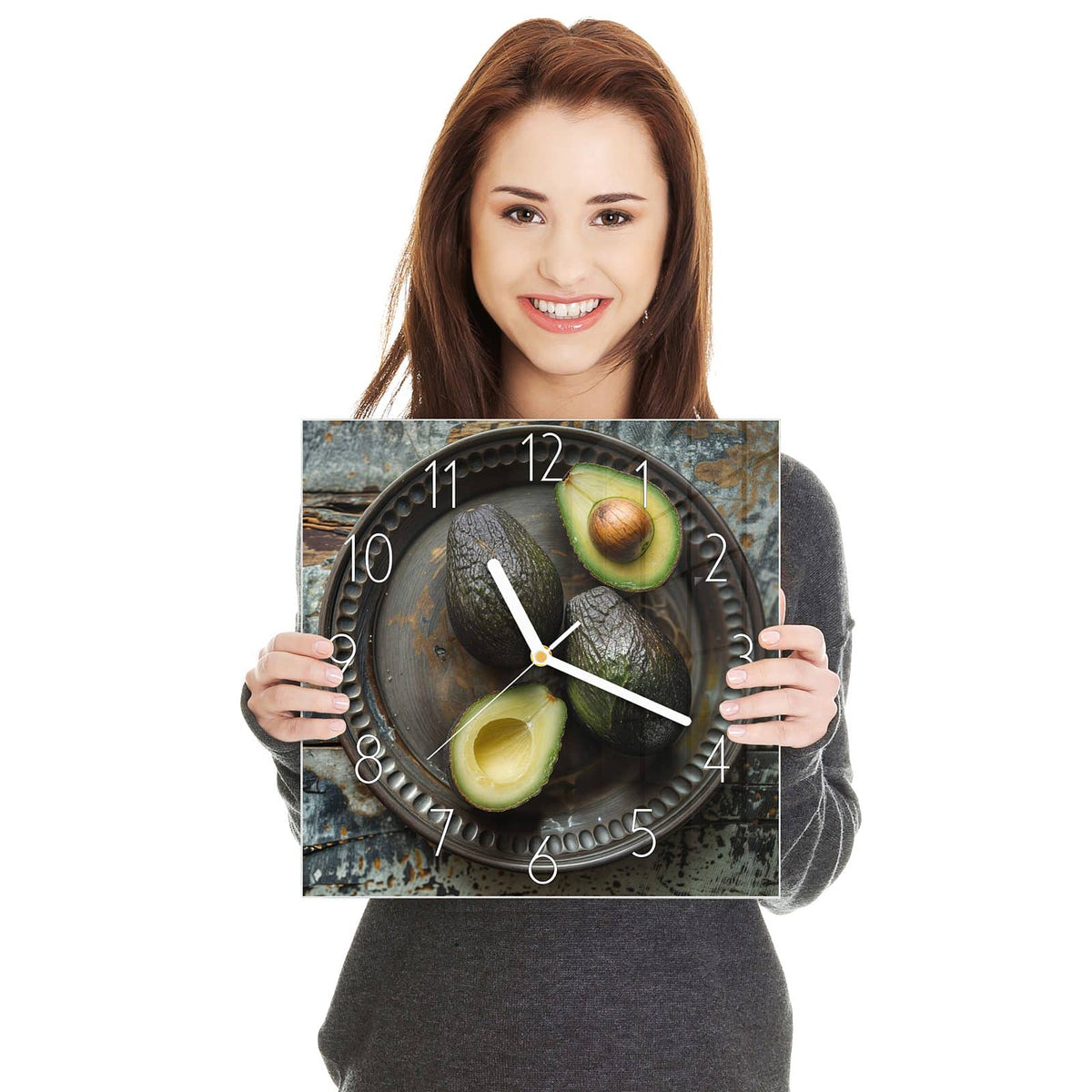 Vier Avocados, zwei davon halbiert, auf dunklem Metallteller mit Perlrand auf verwittertem Holz