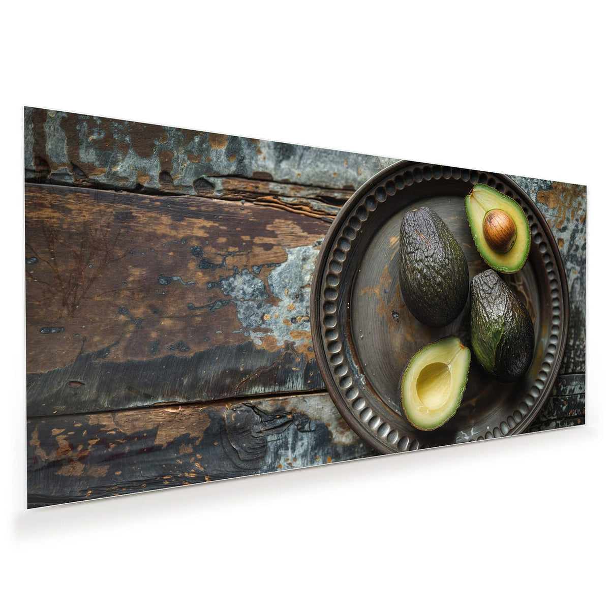 Vier Avocados, zwei davon halbiert, auf dunklem Metallteller mit Perlrand auf verwittertem Holz