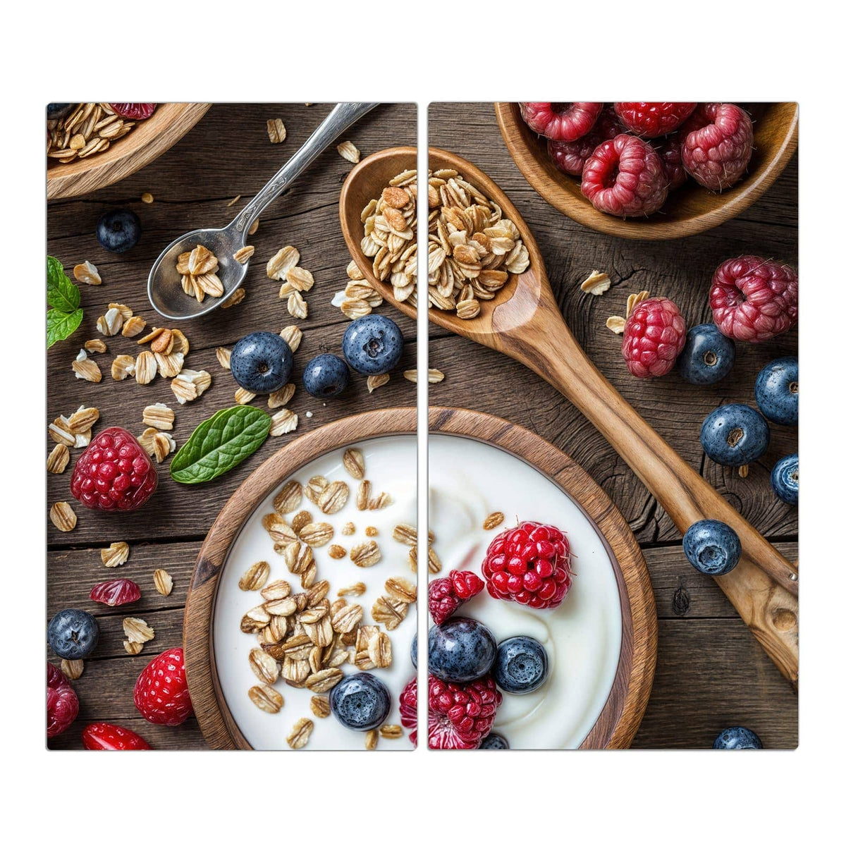 Schale mit Joghurt, Haferflocken, Himbeeren und Blaubeeren, Holzlöffel auf Holztisch