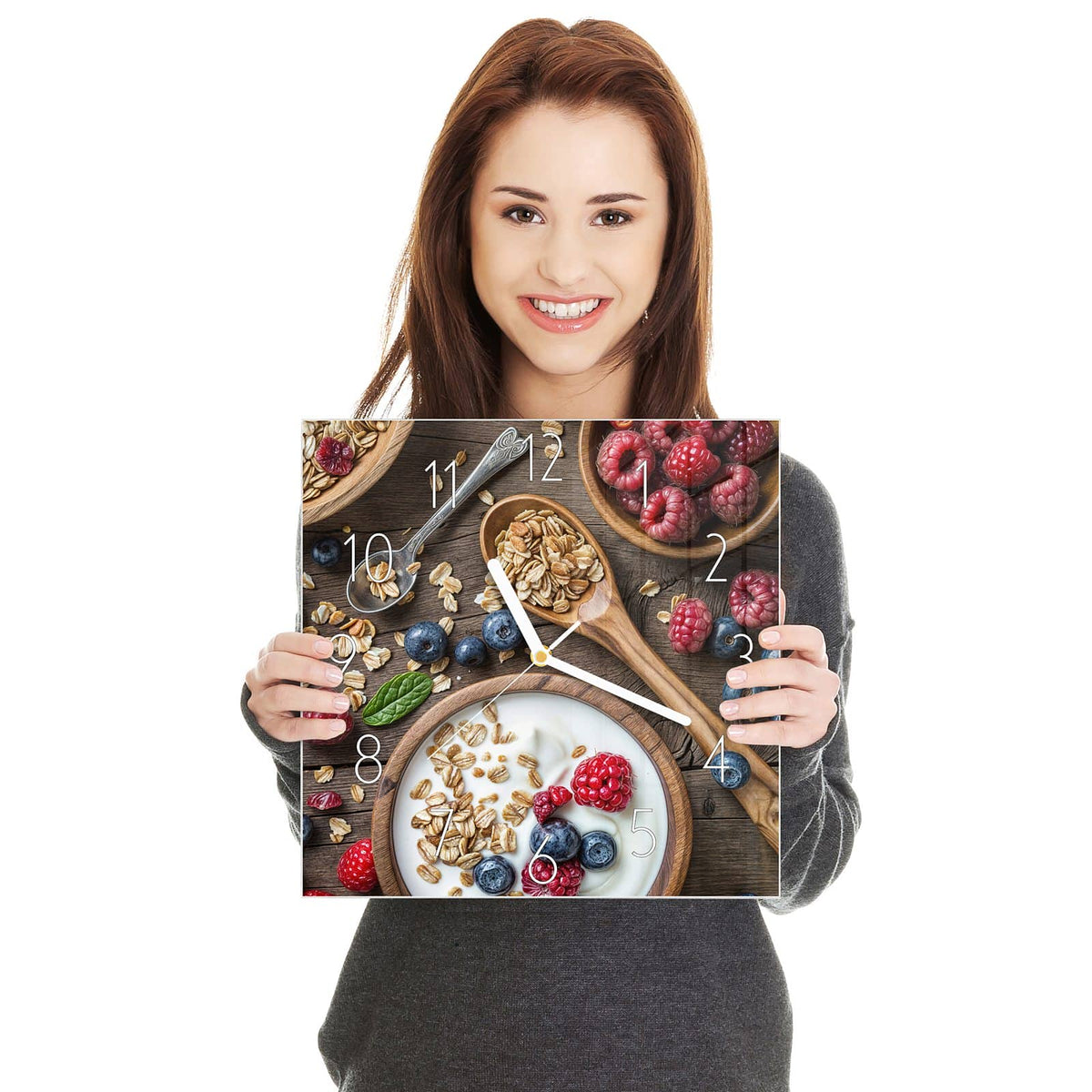 Schale mit Joghurt, Haferflocken, Himbeeren und Blaubeeren, Holzlöffel auf Holztisch