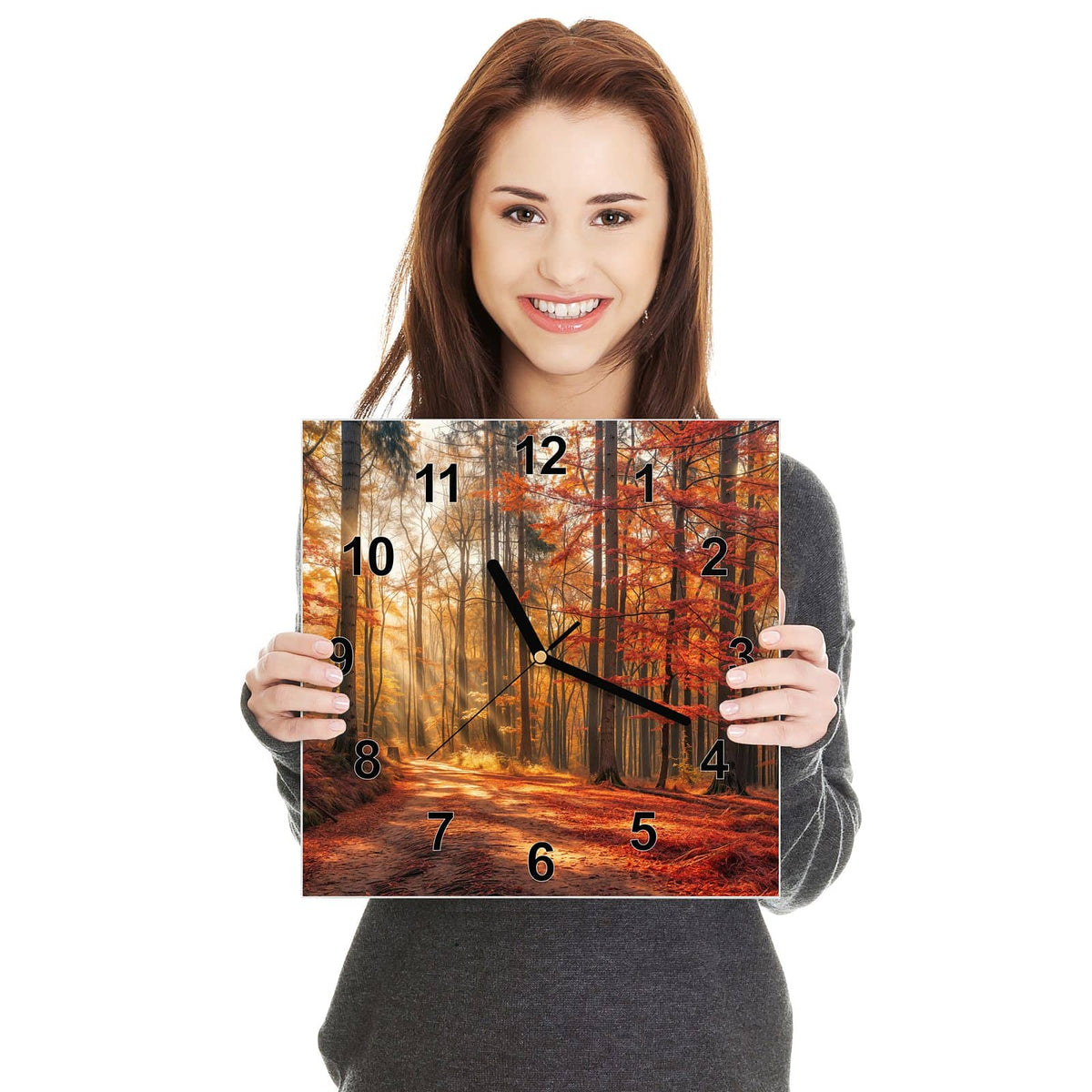 Quadratische Wanduhr aus Glas Waldweg im Herbstlicht in zwei Händen gehalten – Größenvergleich, 30 × 30 cm