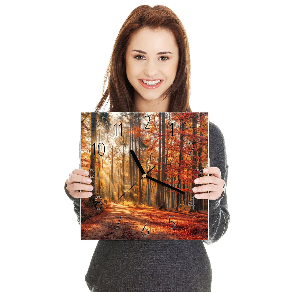 Quadratische Wanduhr aus Glas Waldweg im Herbstlicht in zwei Händen gehalten – Größenvergleich, 30 × 30 cm