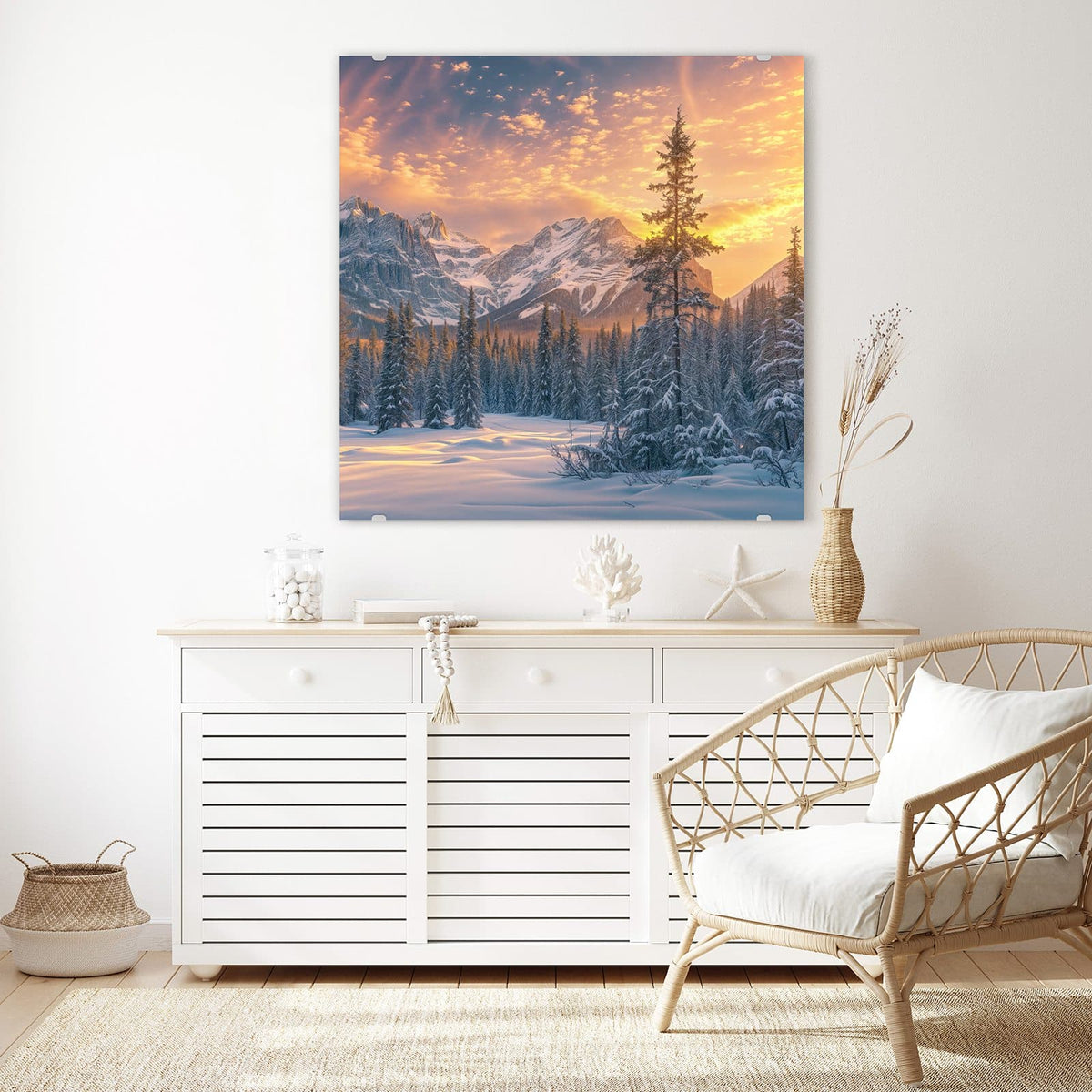 Glasbild Winterwald vor Bergen an der Wand – Verschneiter Nadelwald vor schneebedeckten Bergen unter orange-goldenem Abendhimmel.