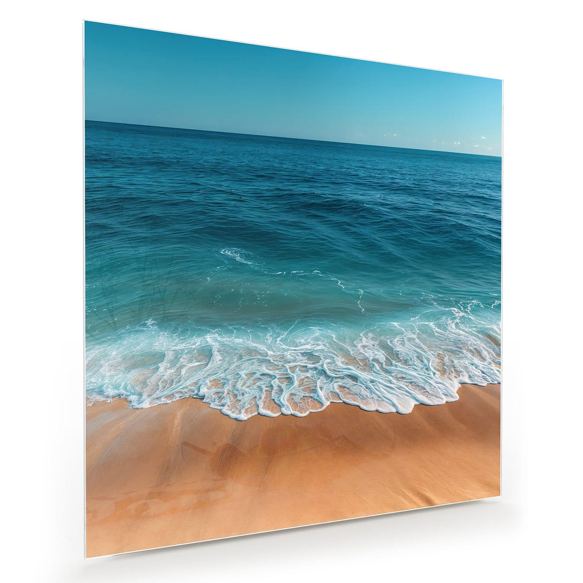 Blick über tiefblaues Meer bis zum Horizont, vorn Schaum auf goldenem Sand