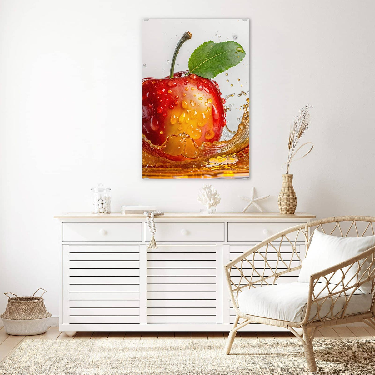 Wandbild aus Glas Apfel mit Saftspritzer über einem weißen Sideboard neben einem Rattansessel