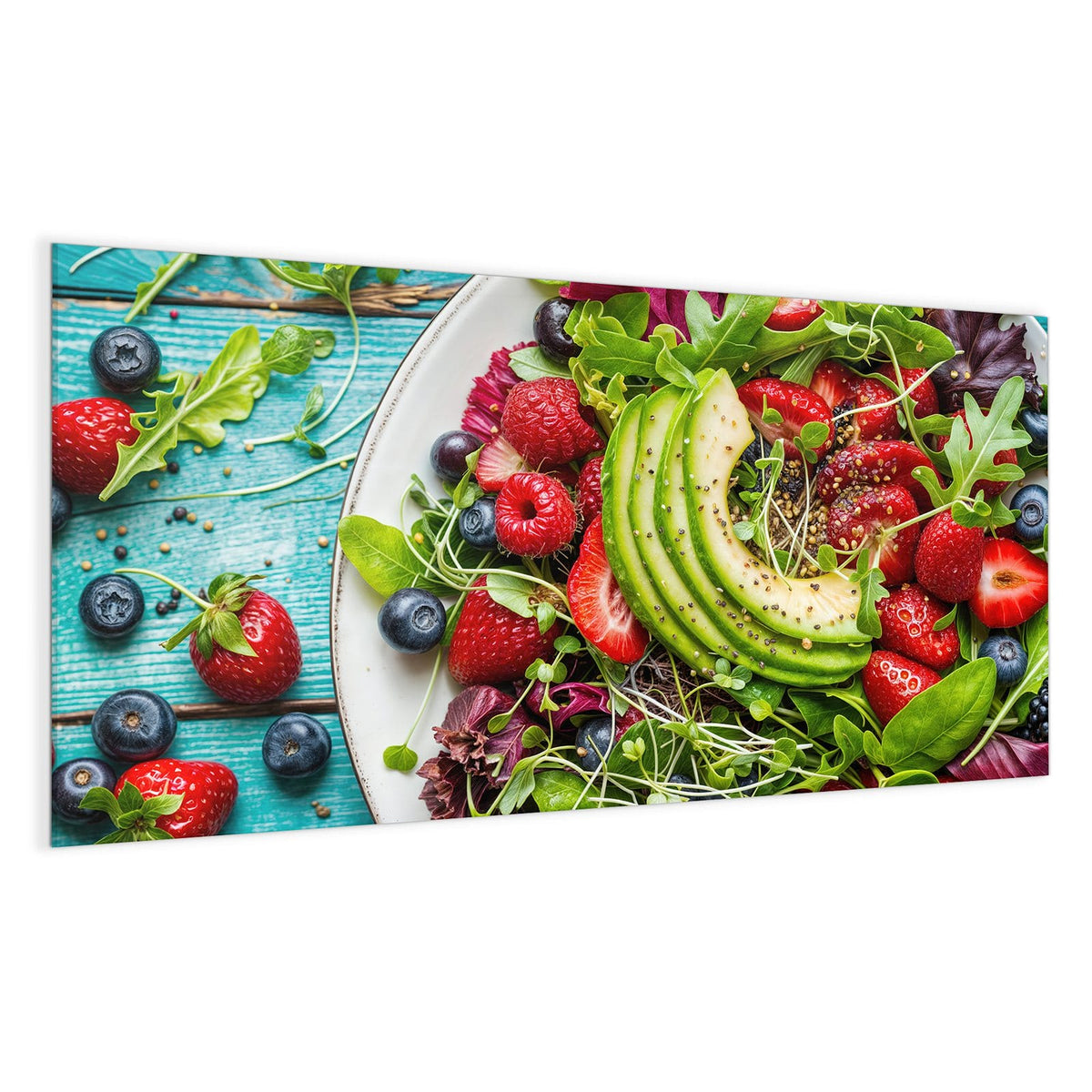 Weißer Teller mit Blattsalat, Avocadoscheiben, Erdbeeren, Himbeeren und Blaubeeren auf türkisem Holz