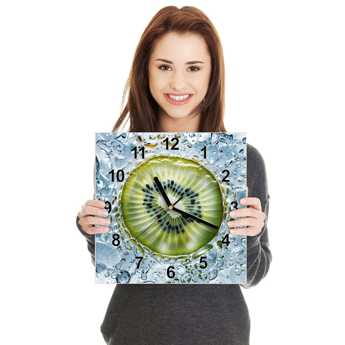 Quadratische Wanduhr aus Glas Kiwi in Wasserblasen in zwei Händen gehalten – Größenvergleich, 30 × 30 cm