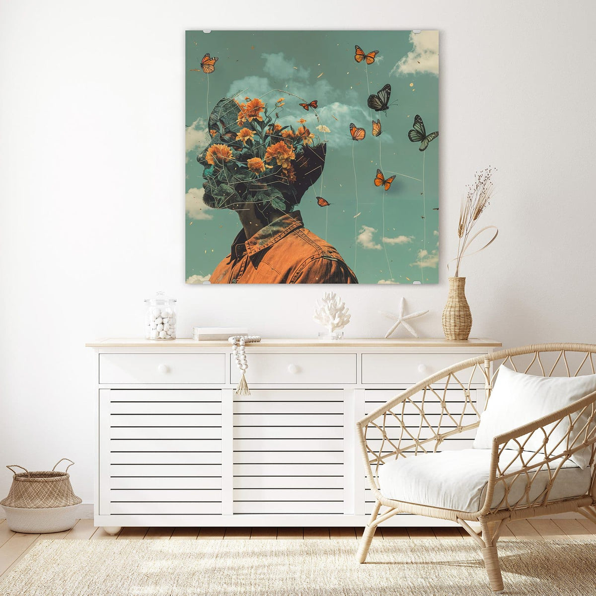 Glasbild Kopf voller Blumen an der Wand – Retro-Collage: Kopf eines Mannes, gefüllt mit orangen Blüten, davor Schmetterlinge an Fäden vor türkisem Wolkenhimmel.