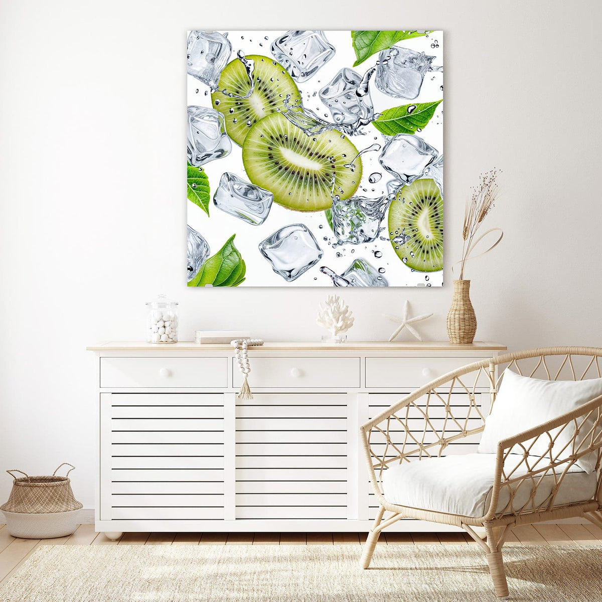 Glasbild Kiwi und Eiswürfel an der Wand – Kiwischeiben zwischen klaren Eiswürfeln und grünen Blättern vor weißem Grund
