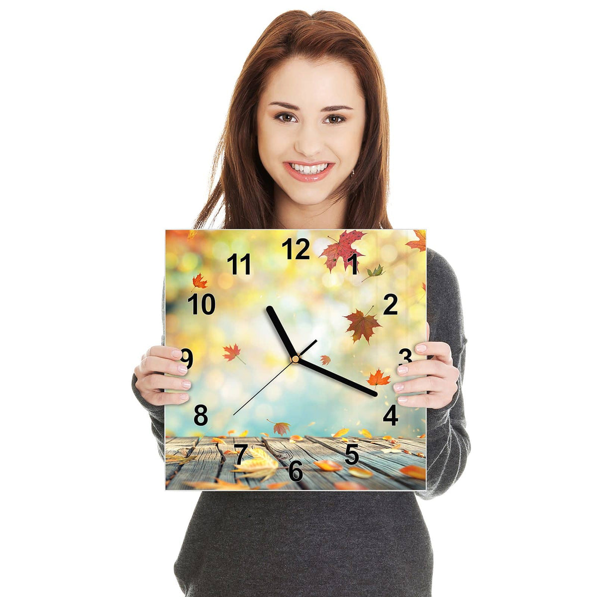 Quadratische Wanduhr aus Glas Herbstlaub auf Holz in zwei Händen gehalten – Größenvergleich, 30 × 30 cm