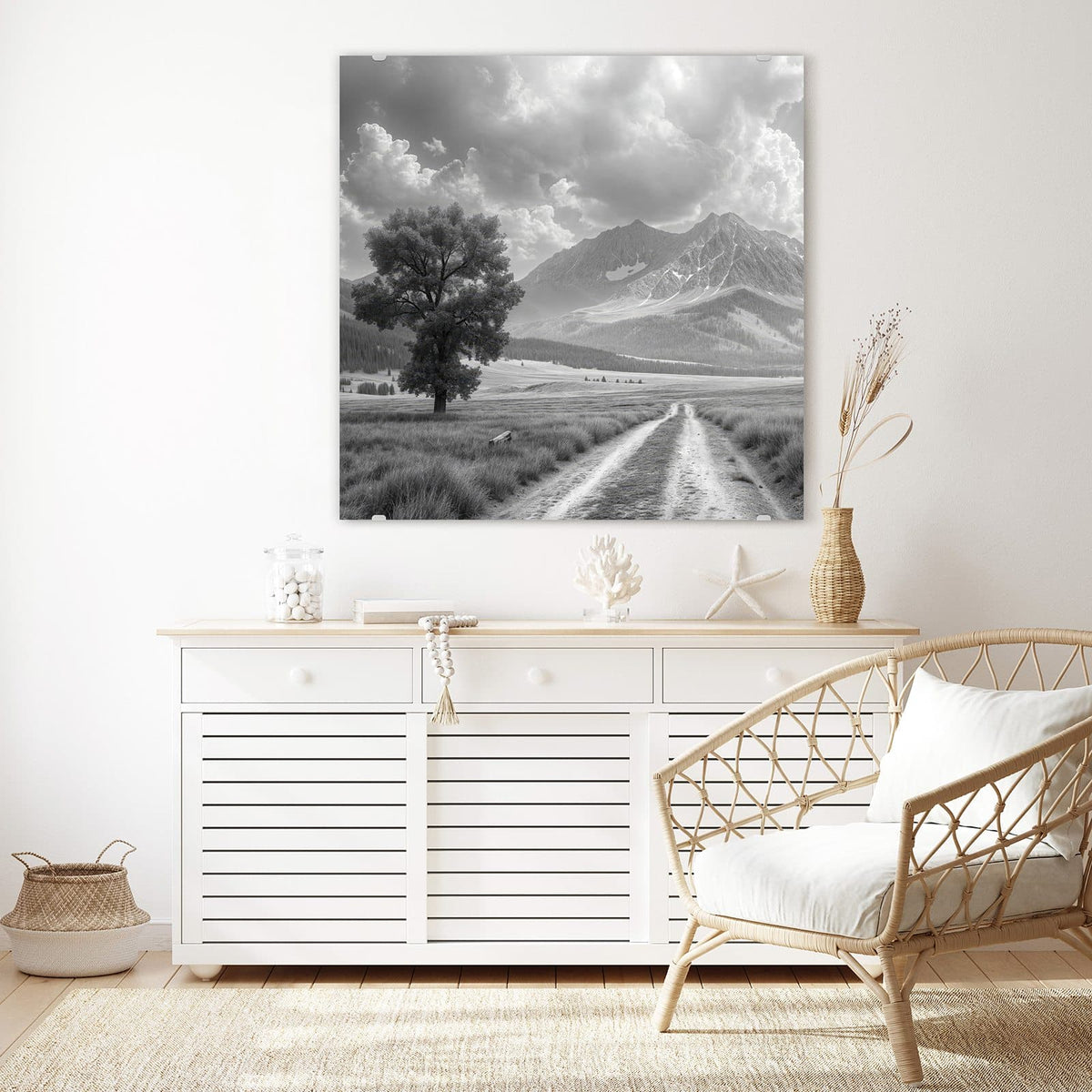 Glasbild Einsamer Baum vor Bergen an der Wand – Schwarzweißfoto: einzelner Baum links an einem Feldweg, dahinter Bergkette mit Wolkentürmen.