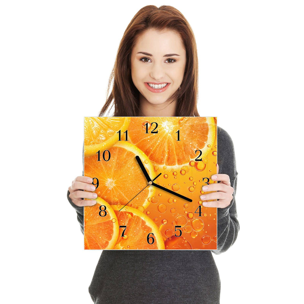 Quadratische Wanduhr aus Glas Sprudelnde Orangen in zwei Händen gehalten – Größenvergleich, 30 × 30 cm