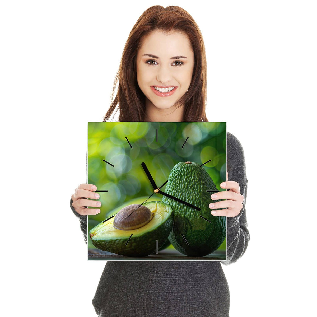 Quadratische Wanduhr aus Glas Halbierte Avocado in zwei Händen gehalten – Größenvergleich, 30 × 30 cm