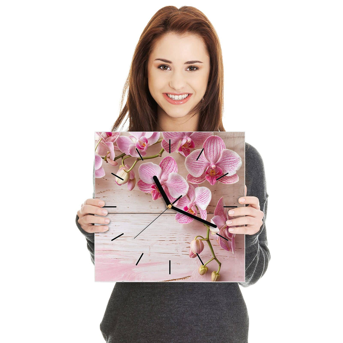 Quadratische Wanduhr aus Glas Orchideen auf Rosa in zwei Händen gehalten – Größenvergleich, 30 × 30 cm