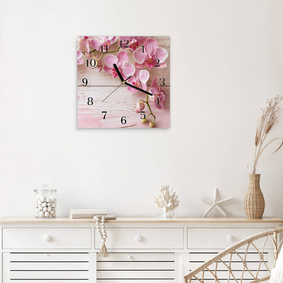 Quadratische Wanduhr aus Glas Orchideen auf Rosa mit Ziffernblatt Klassisch über einem weißen Sideboard