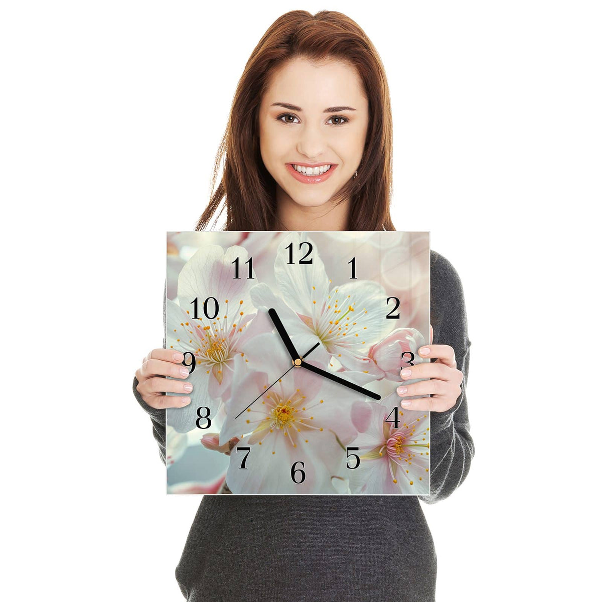 Quadratische Wanduhr aus Glas Weiße Frühlingsblüten in zwei Händen gehalten – Größenvergleich, 30 × 30 cm