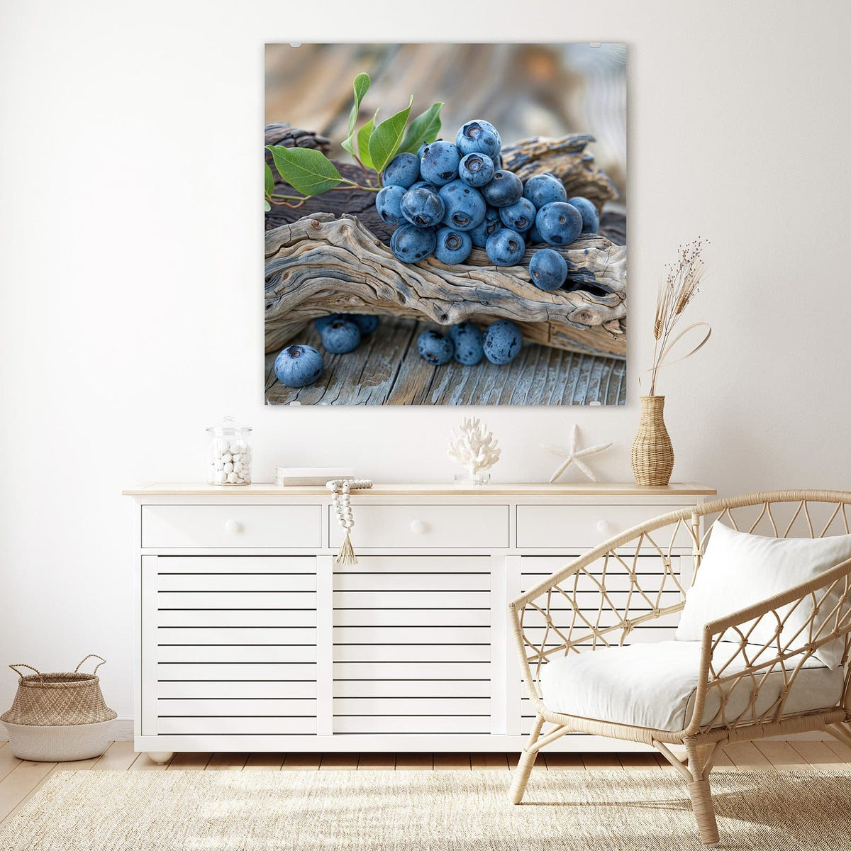 Glasbild Treibholz und Blaubeeren an der Wand – Haufen Blaubeeren mit grünen Blättern auf verwittertem Treibholzast, darunter graue Holzdielen