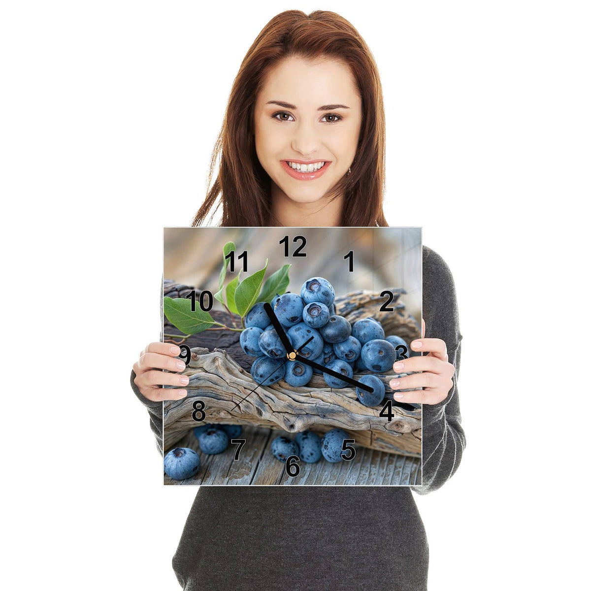 Quadratische Wanduhr aus Glas Treibholz und Blaubeeren in zwei Händen gehalten – Größenvergleich, 30 × 30 cm