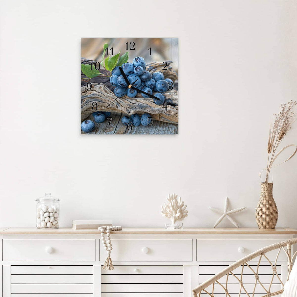 Quadratische Wanduhr aus Glas Treibholz und Blaubeeren mit Ziffernblatt Klassisch über einem weißen Sideboard