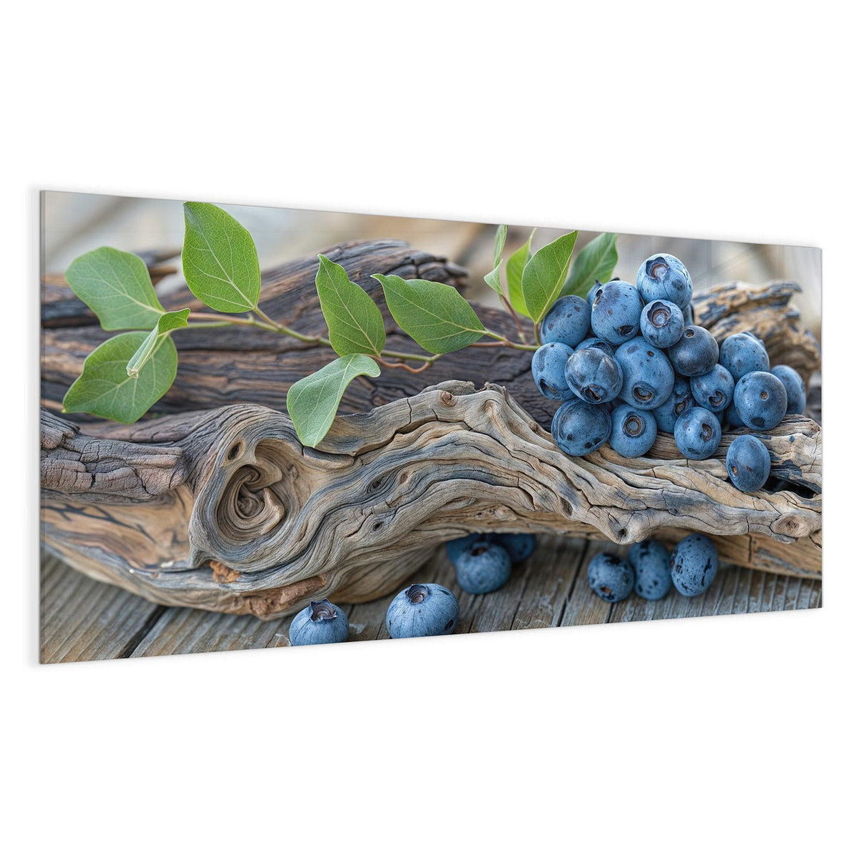 Haufen Blaubeeren mit grünen Blättern auf verwittertem Treibholzast, darunter graue Holzdielen