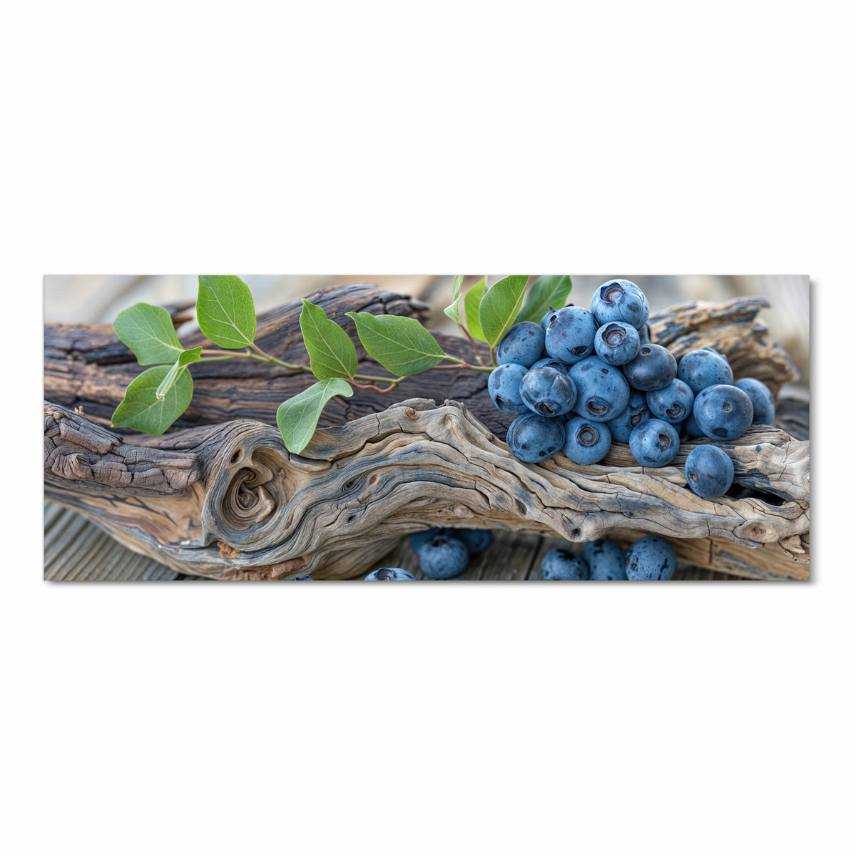 Haufen Blaubeeren mit grünen Blättern auf verwittertem Treibholzast, darunter graue Holzdielen