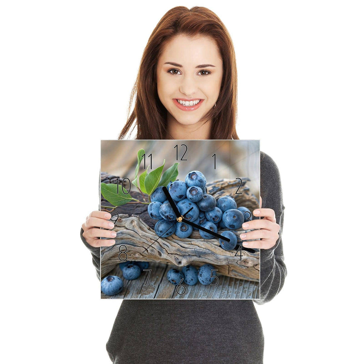 Quadratische Wanduhr aus Glas Treibholz und Blaubeeren in zwei Händen gehalten – Größenvergleich, 30 × 30 cm