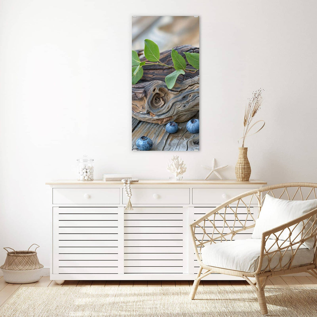 Glasbild Treibholz und Blaubeeren an der Wand – Haufen Blaubeeren mit grünen Blättern auf verwittertem Treibholzast, darunter graue Holzdielen