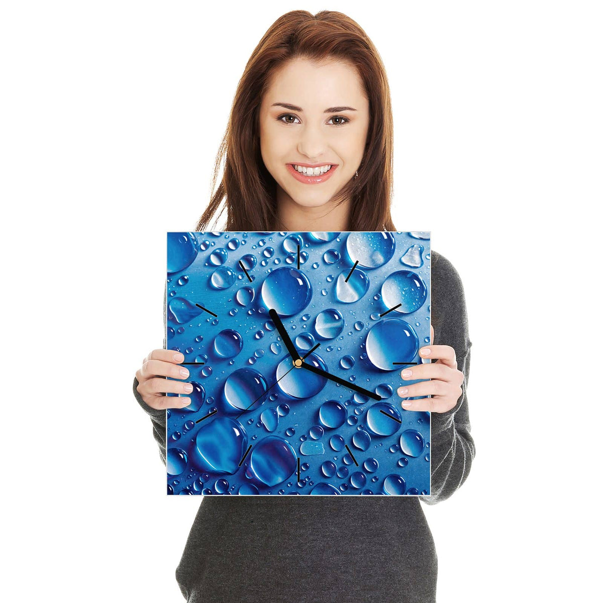 Quadratische Wanduhr aus Glas Tropfen auf Blau in zwei Händen gehalten – Größenvergleich, 30 × 30 cm