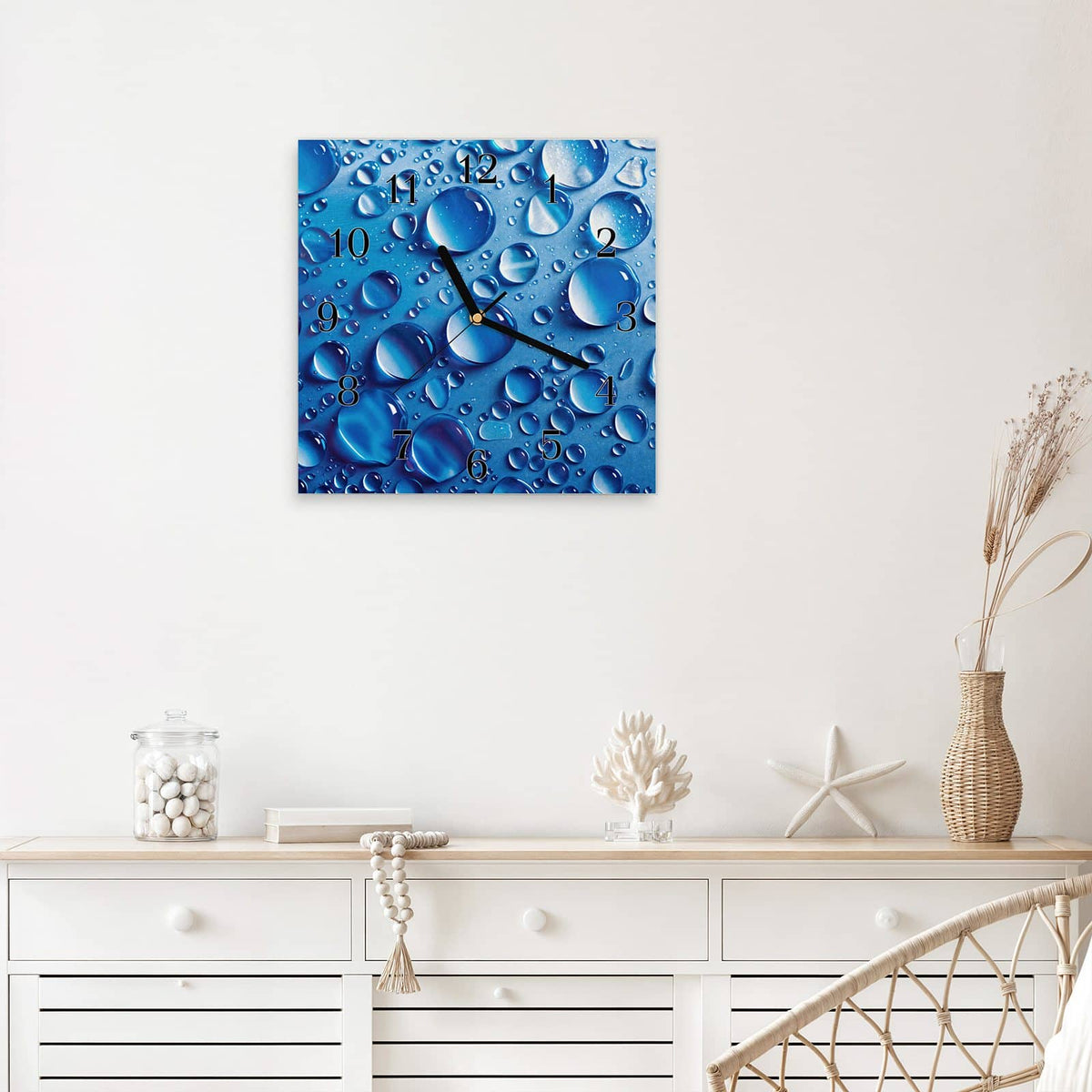 Quadratische Wanduhr aus Glas Tropfen auf Blau mit Ziffernblatt Klassisch über einem weißen Sideboard