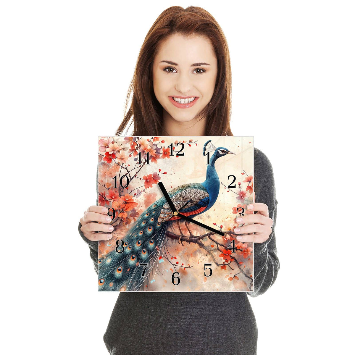 Quadratische Wanduhr aus Glas Pfau auf Kirschzweig in zwei Händen gehalten – Größenvergleich, 30 × 30 cm