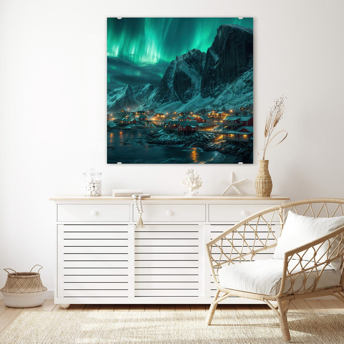 Glasbild Nordlichter über Fjord an der Wand – Grünes Polarlicht über verschneiten Felsen und einem beleuchteten roten Fischerdorf am Wasser