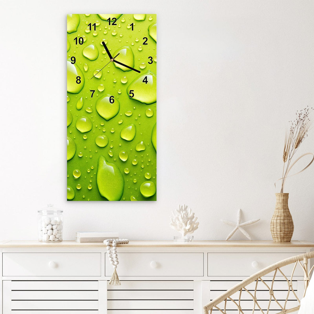 Wanduhr aus Glas im Hochformat Tropfen auf Grün mit Ziffernblatt Modern über einem weißen Sideboard