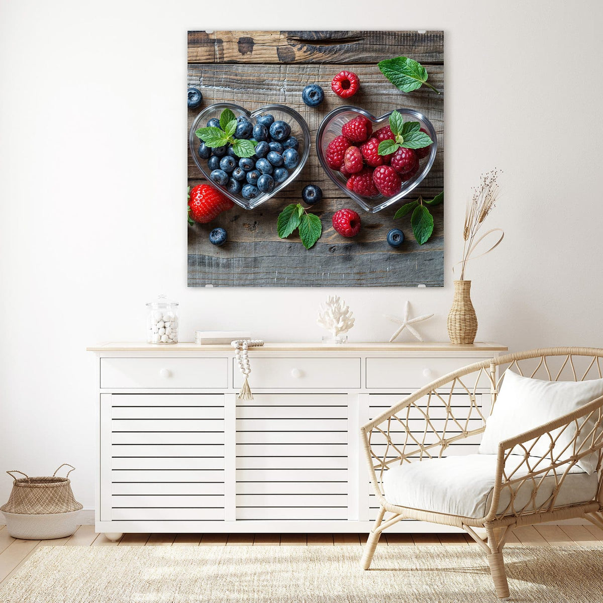 Glasbild Beeren in Herzschalen an der Wand – Zwei herzförmige Glasschalen auf Holz, eine mit Blaubeeren, eine mit Himbeeren, dazu Minzblätter.