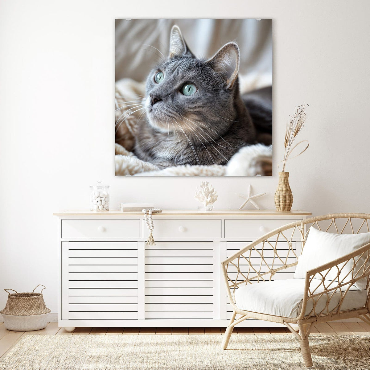 Glasbild Graue Katze auf Decke an der Wand – Graue Katze mit grüntürkisen Augen liegt auf einer flauschigen hellen Decke, Blick nach oben