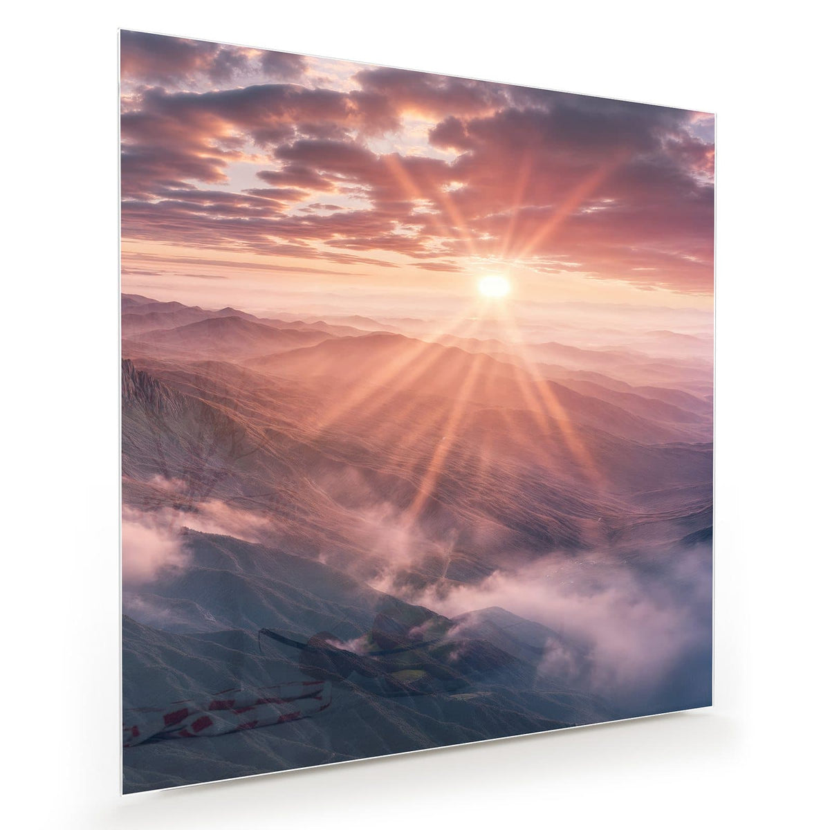 Sonne mit Strahlenkranz über nebligen Bergkämmen, rosa Wolken.