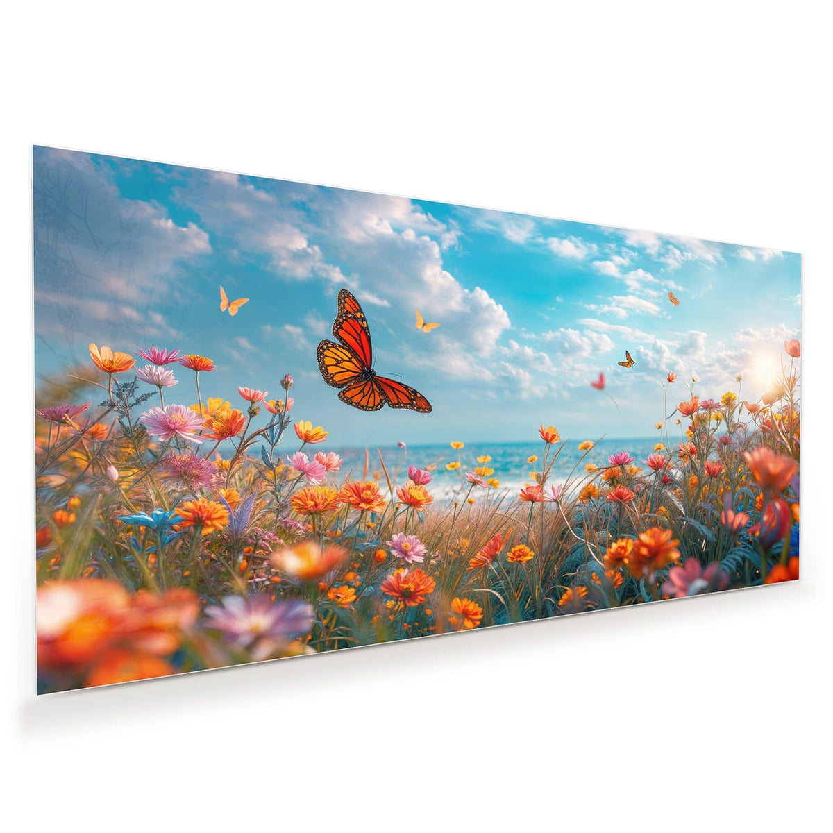 Bunte Blumenwiese am Meer mit Monarchfalter, dahinter türkises Wasser und Wolkenhimmel