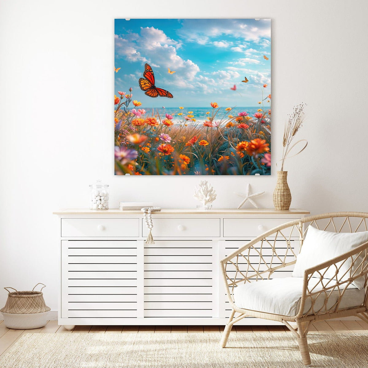 Glasbild Blütenwiese am Meer an der Wand – Bunte Blumenwiese am Meer mit Monarchfalter, dahinter türkises Wasser und Wolkenhimmel