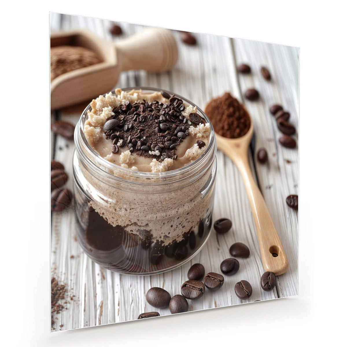 Cremiges Kaffeedessert im Glas mit Schokoraspeln, daneben ein Holzlöffel mit Kakao und Bohnen