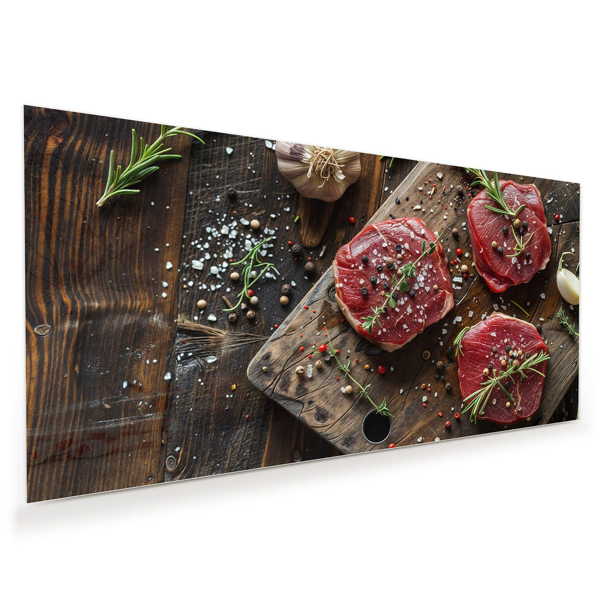 Drei rohe Rindersteaks auf Holzbrett mit Rosmarin, Knoblauch, Salz und Pfefferkörnern