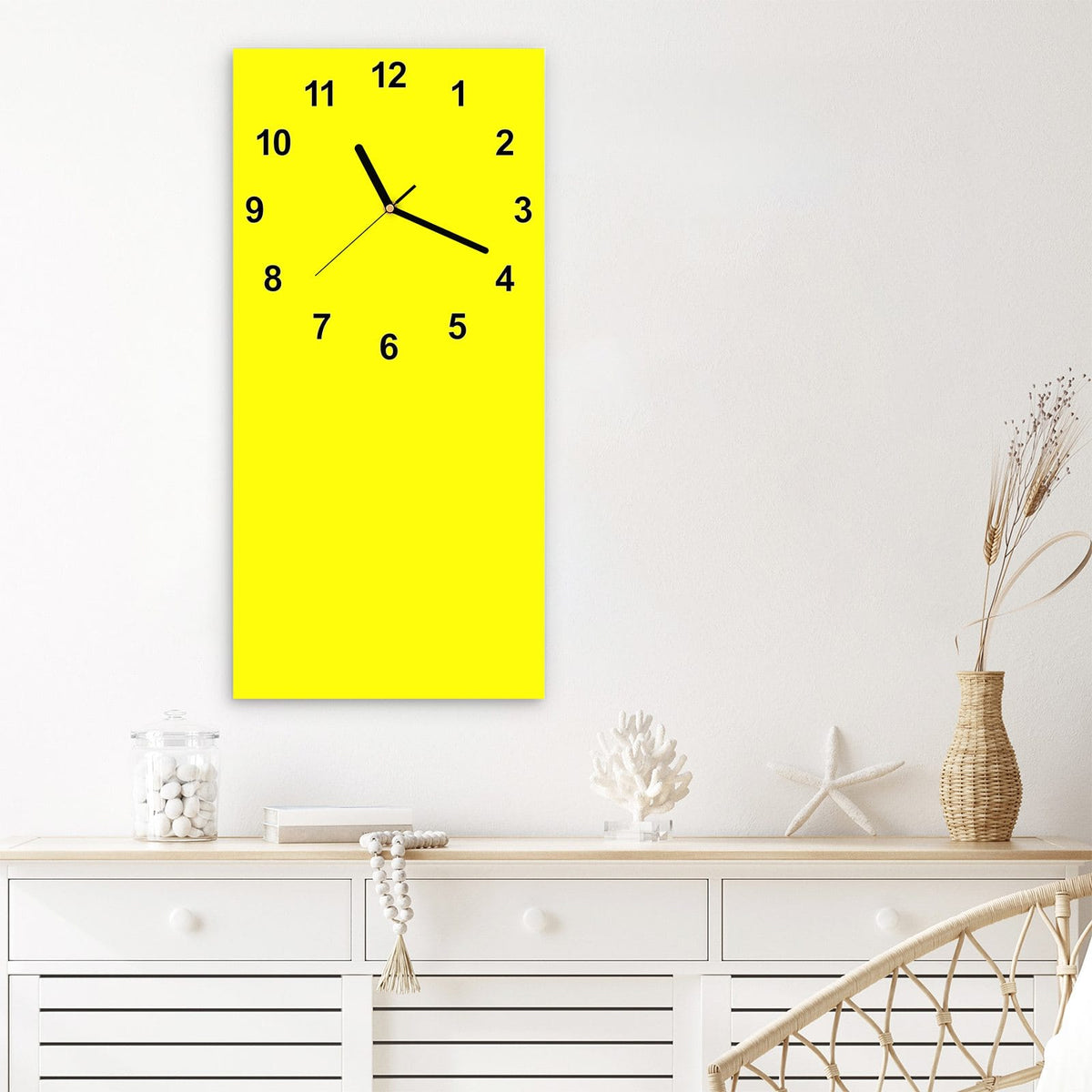 Wanduhr aus Glas im Hochformat Zitronengelb mit Ziffernblatt Modern über einem weißen Sideboard