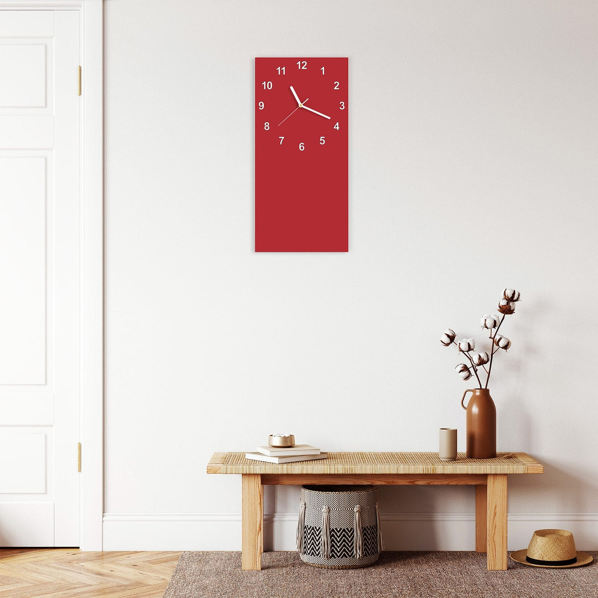 Wanduhr aus Glas im Hochformat Kirschrot mit Ziffernblatt Modern über einer Holzbank im Flur