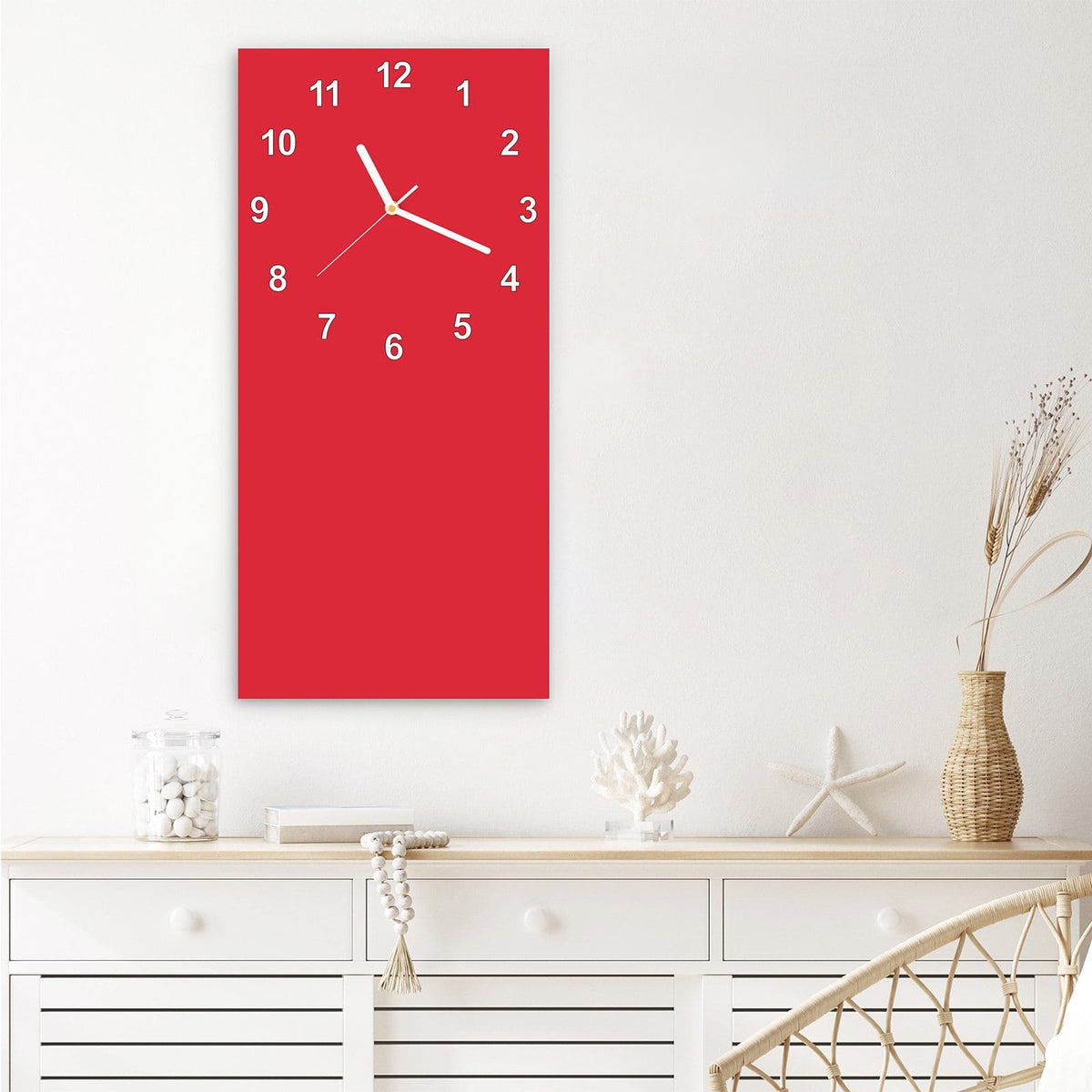 Wanduhr aus Glas im Hochformat Pinkroter Hintergrund mit Ziffernblatt Modern über einem weißen Sideboard
