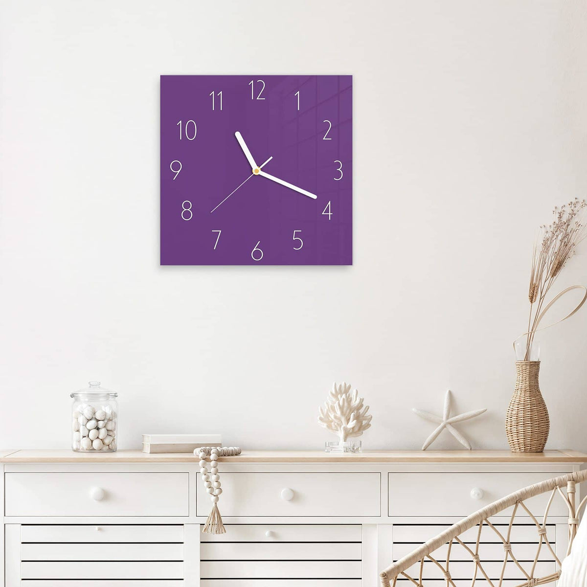 Quadratische Wanduhr aus Glas Pflaumenlila mit Ziffernblatt Elegant über einem weißen Sideboard