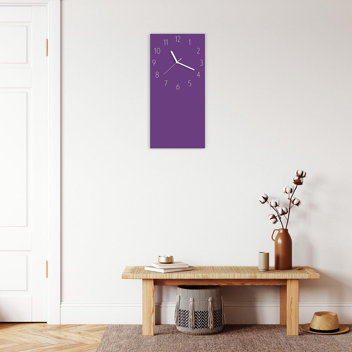 Wanduhr aus Glas im Hochformat Pflaumenlila mit Ziffernblatt Elegant über einer Holzbank im Flur