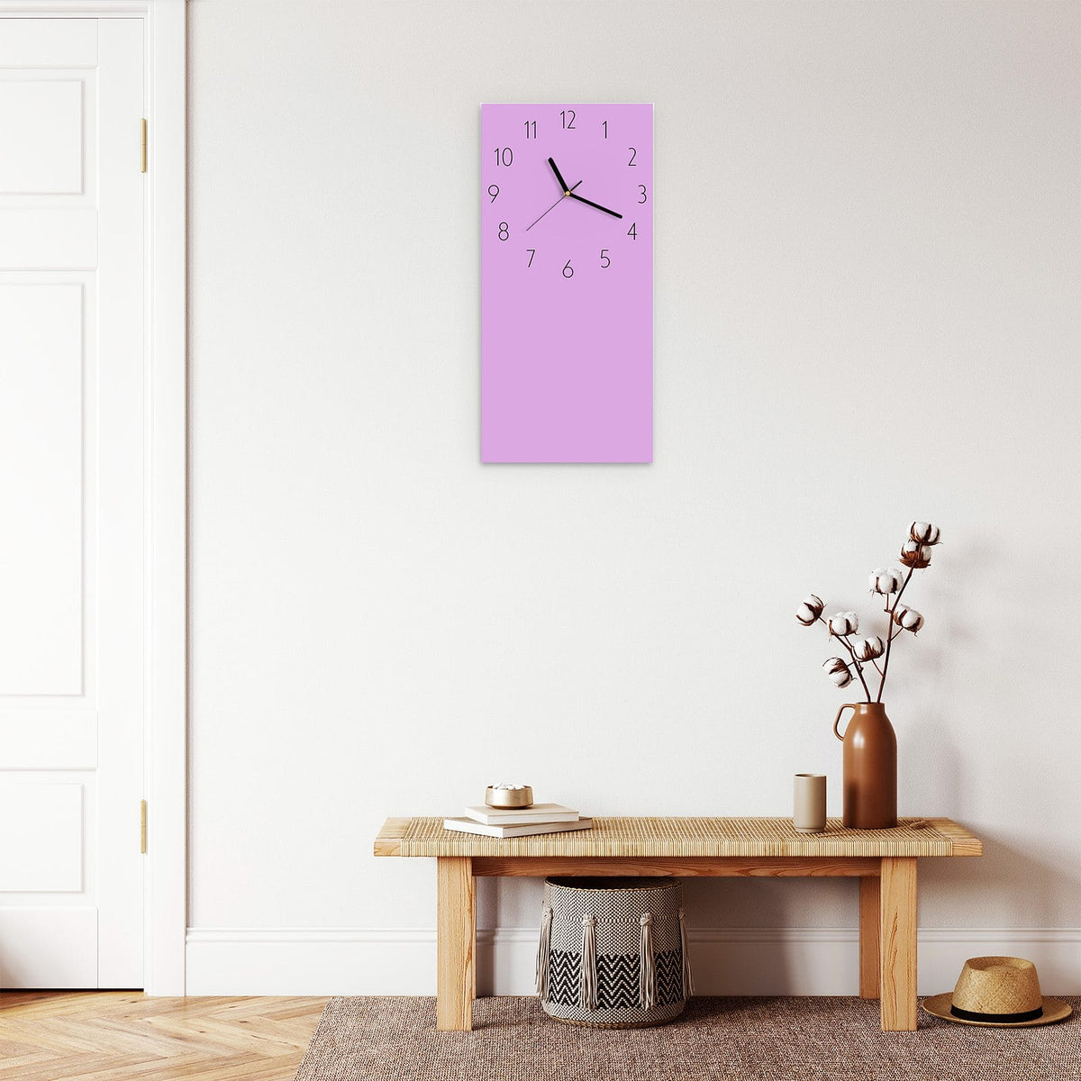 Wanduhr aus Glas im Hochformat Fliederlila mit Ziffernblatt Elegant über einer Holzbank im Flur